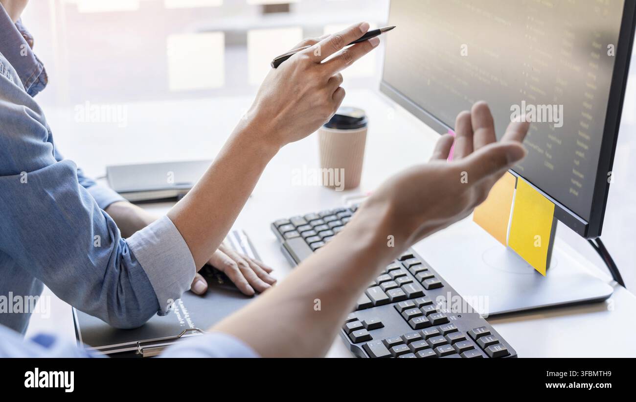 Young startup Programmers Sitting At Desks Working On Computers screen for Developing programming and coding to find solution to problem on New Applic Stock Photo
