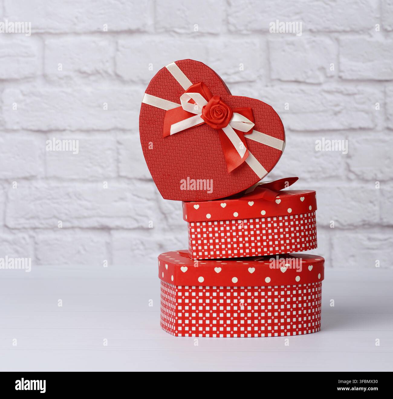 Stack of various red boxes with gifts on white background, festive backdrop Stock Photo