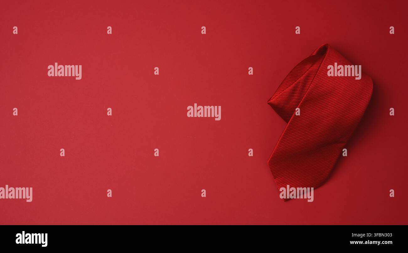 Twisted silk red tie on a red background, copy space Stock Photo