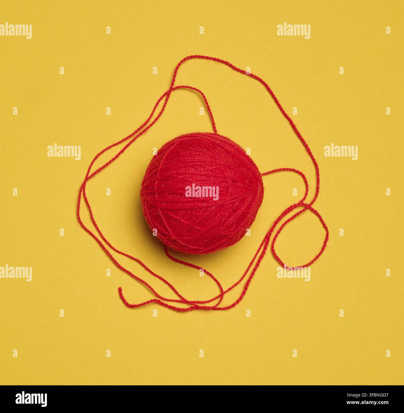Ball of red woolen thread on yellow background, top view Stock Photo