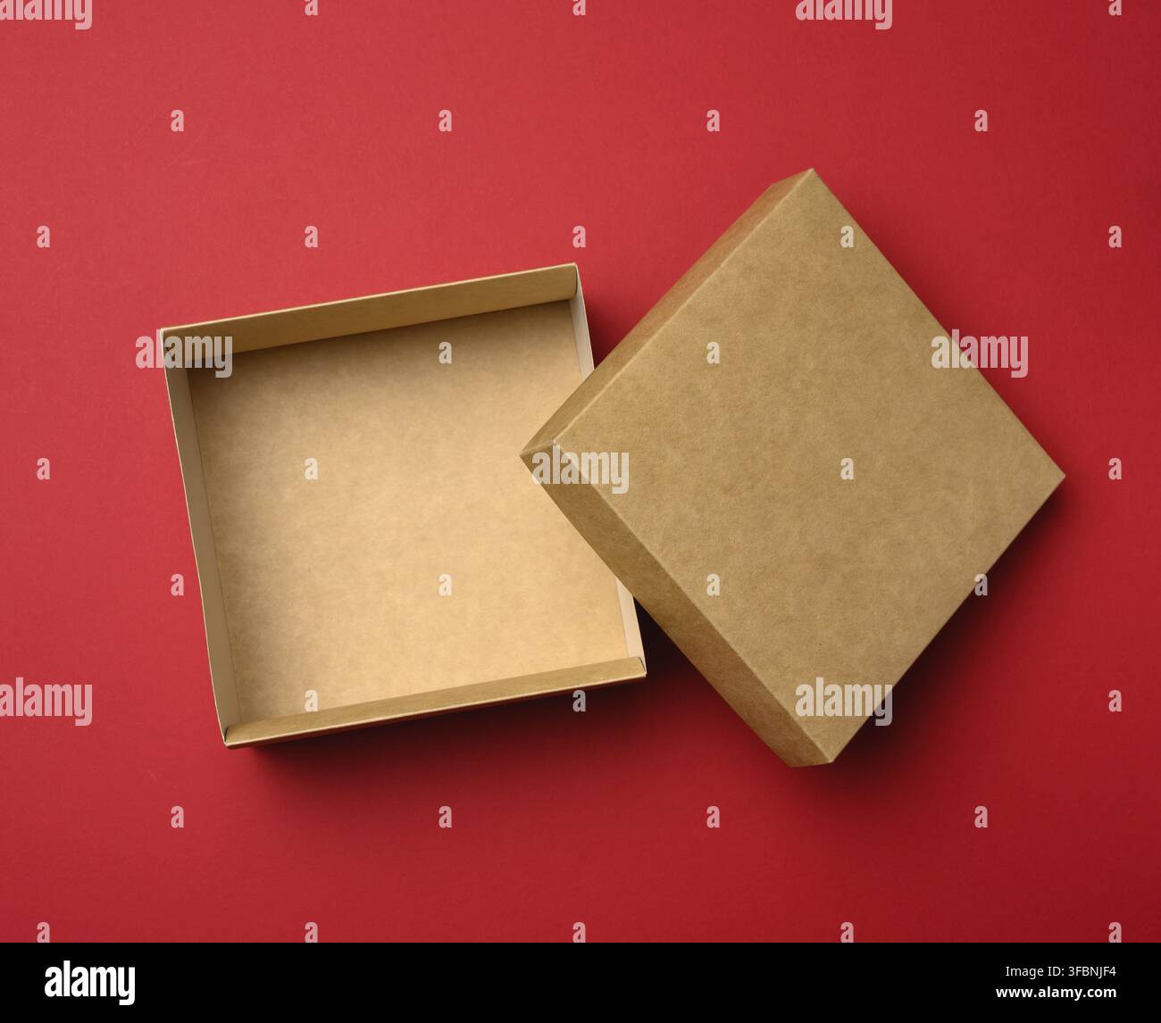 Empty square brown box on a red background, gift open, top view Stock Photo