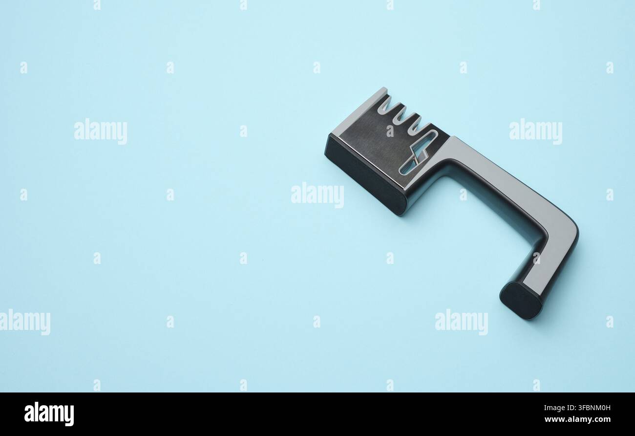 Manual sharpener for kitchen knives on a blue background, copy space Stock Photo