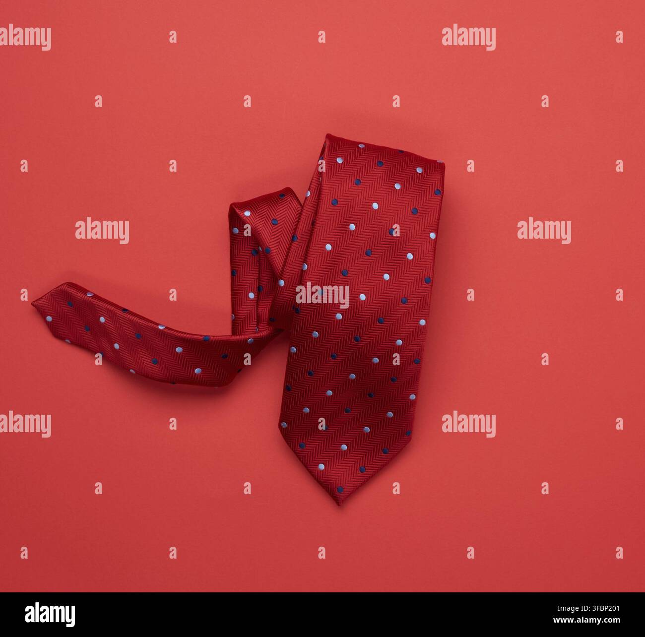 Twisted silk red tie on red background, top view Stock Photo