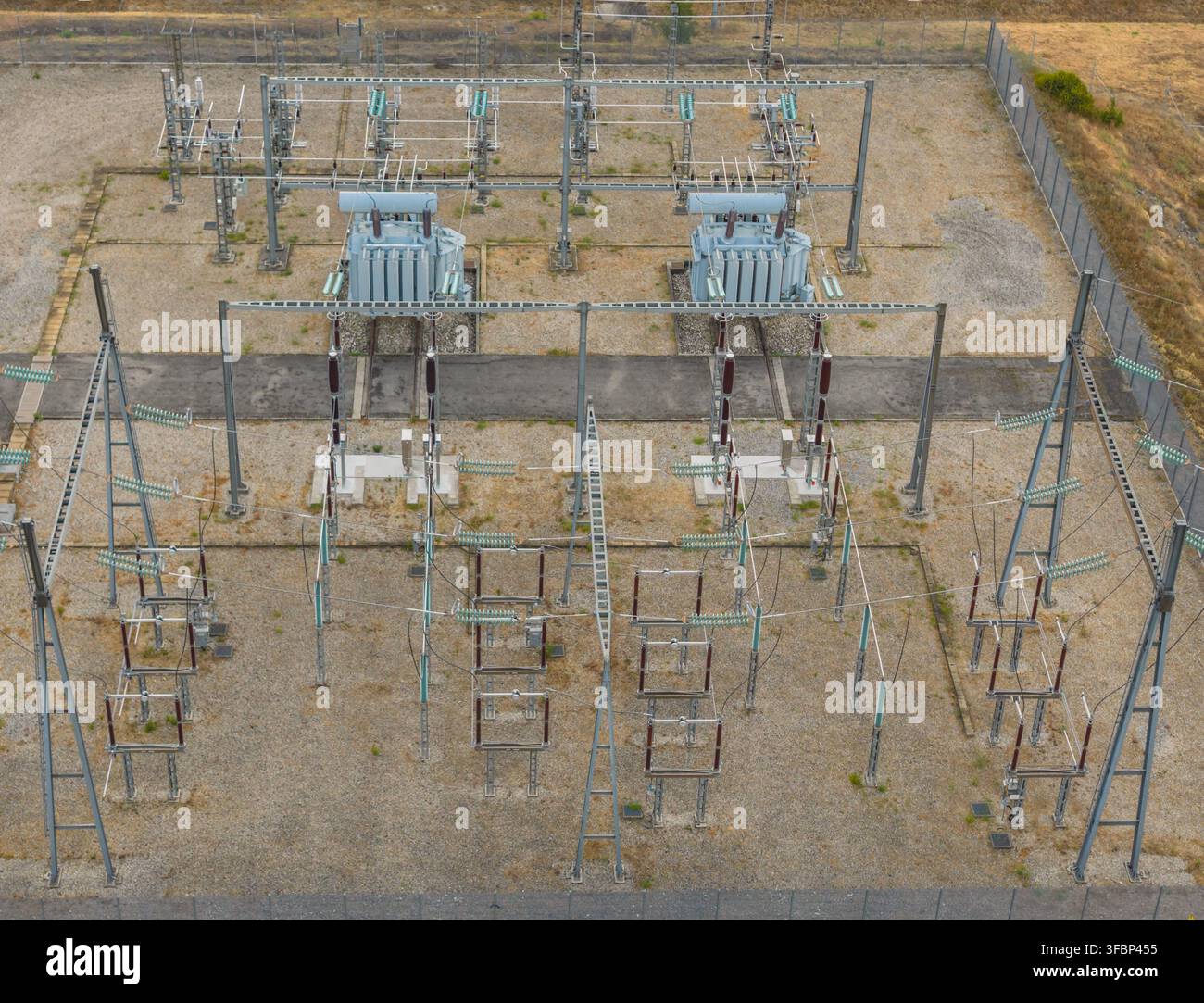 Aerial view of electrical substation infrastructure with two large power transformers, high voltage insulators, switchgear and transmission equipment Stock Photo