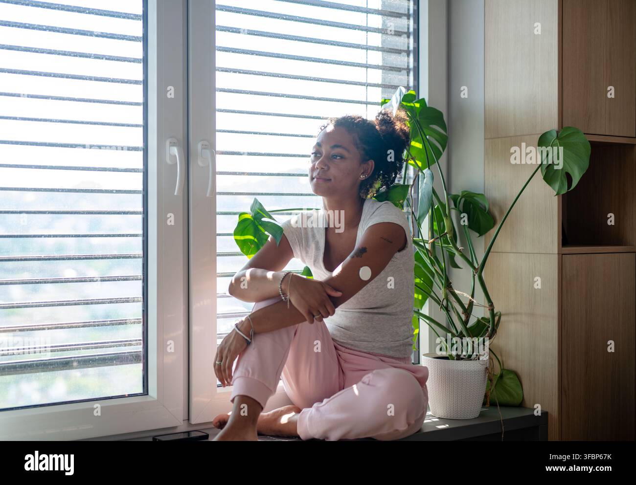 Female diabetes patient with CGM sensor in bright apartment Stock Photo