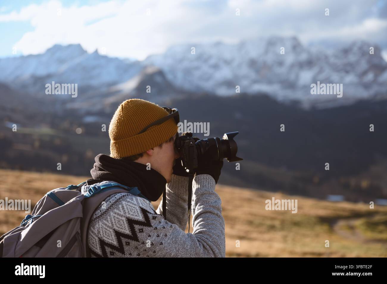 Photographer capturing mountain scenery during autumn in the Dolomites. Outdoor travel and landscape photography with snow-covered peaks in the background Stock Photo