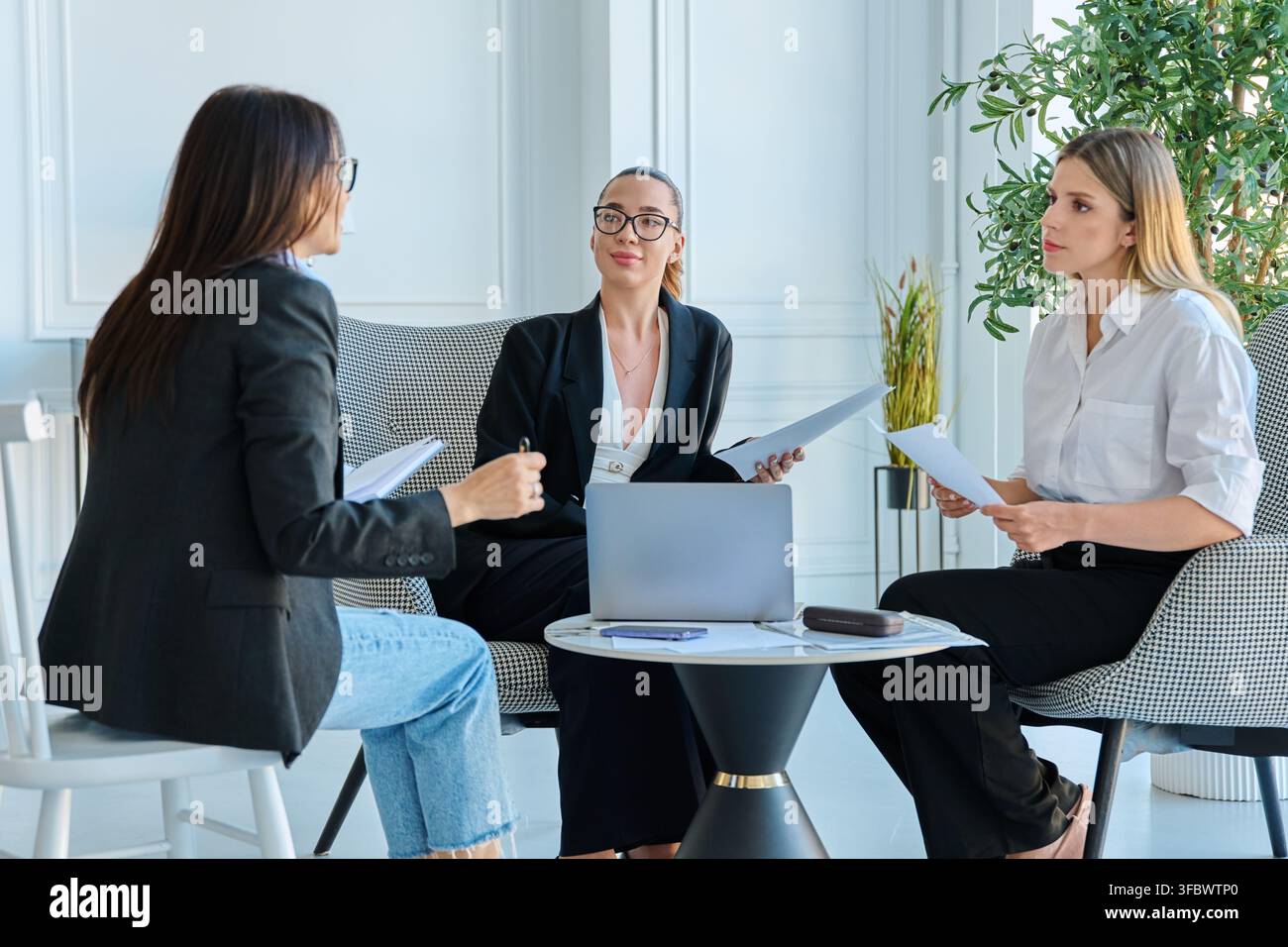 Group of diverse businesswomen discussing project documents during meeting in office Stock Photo