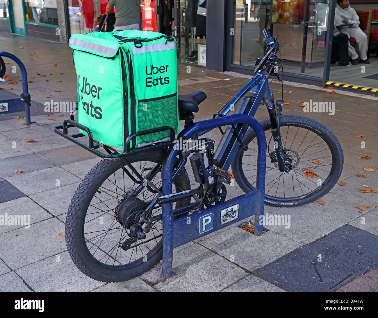 Uber Eats delivery bicycle with large insulated courier bag parked in a British town centre. Stock Photo