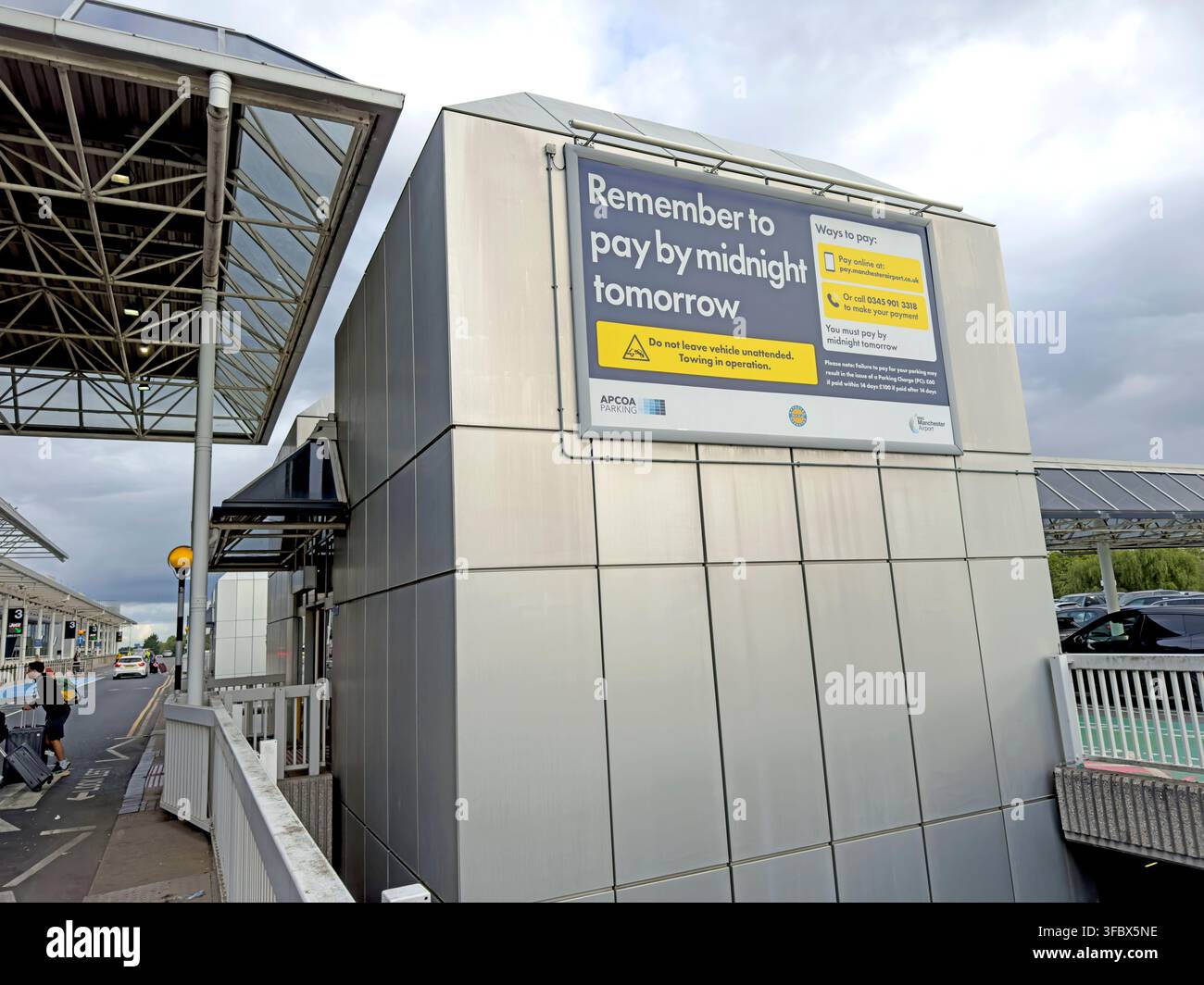 Manchester Airport Terminal 2 exterior with a large reminder sign for barrierless drop-off payment by the following midnight. Stock Photo