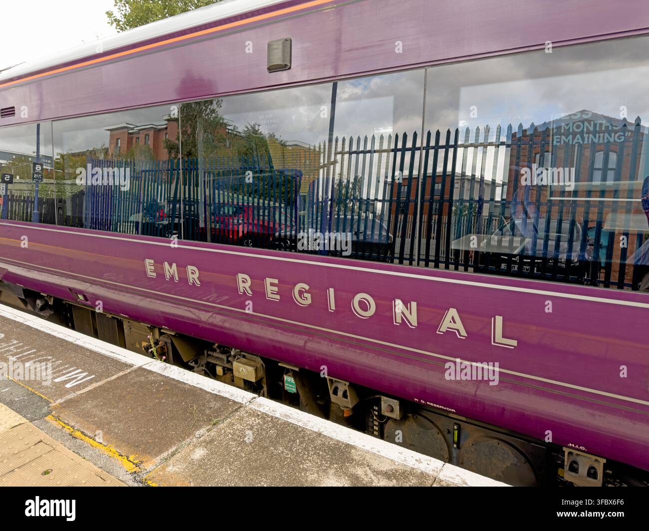 East Midlands Railway Regional train at Warrington Central station platform east bound, showing EMR purple livery and passenger carriage. Stock Photo