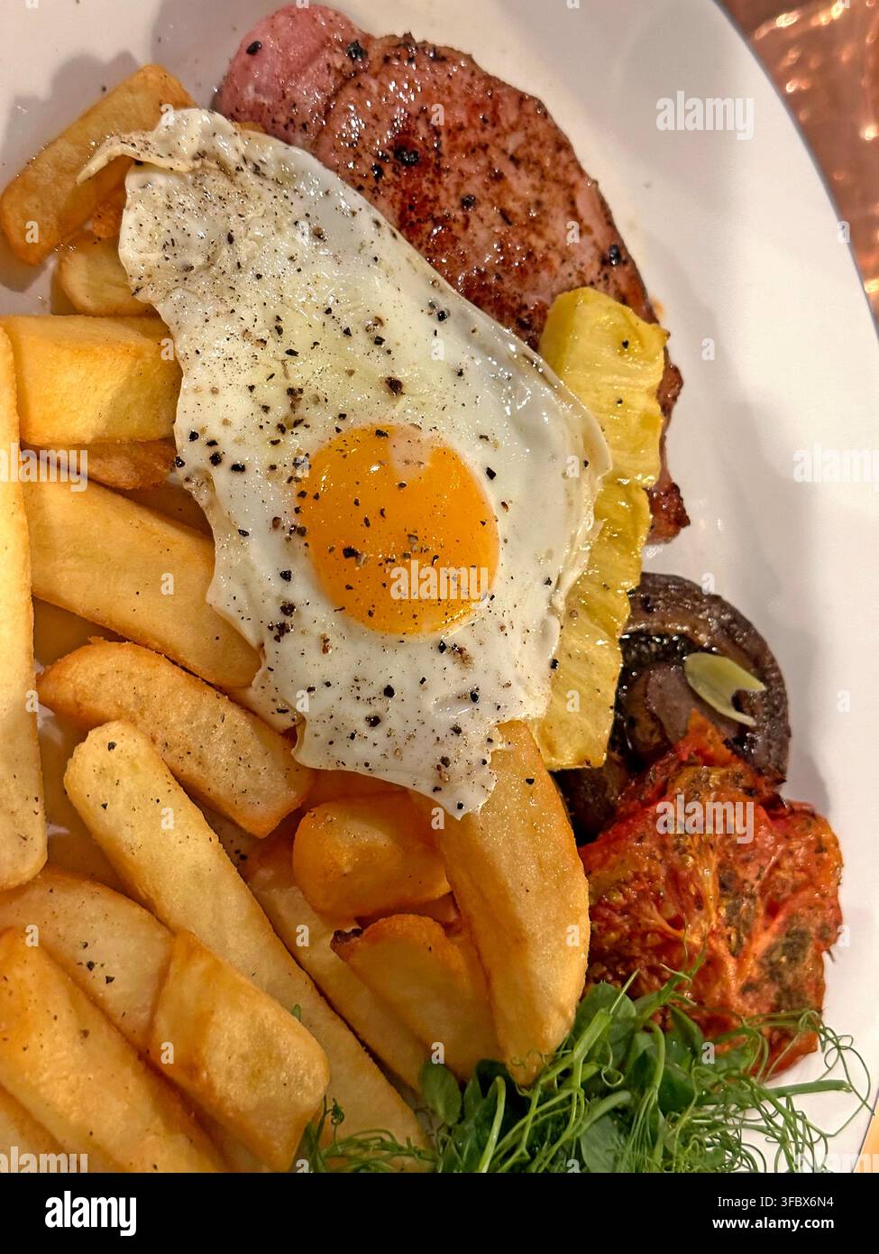 Soft runny fried egg with gammon, chips and cooked breakfast ingredients in a British cafe or pub, illustrating August 2026 Salmonella concerns Stock Photo
