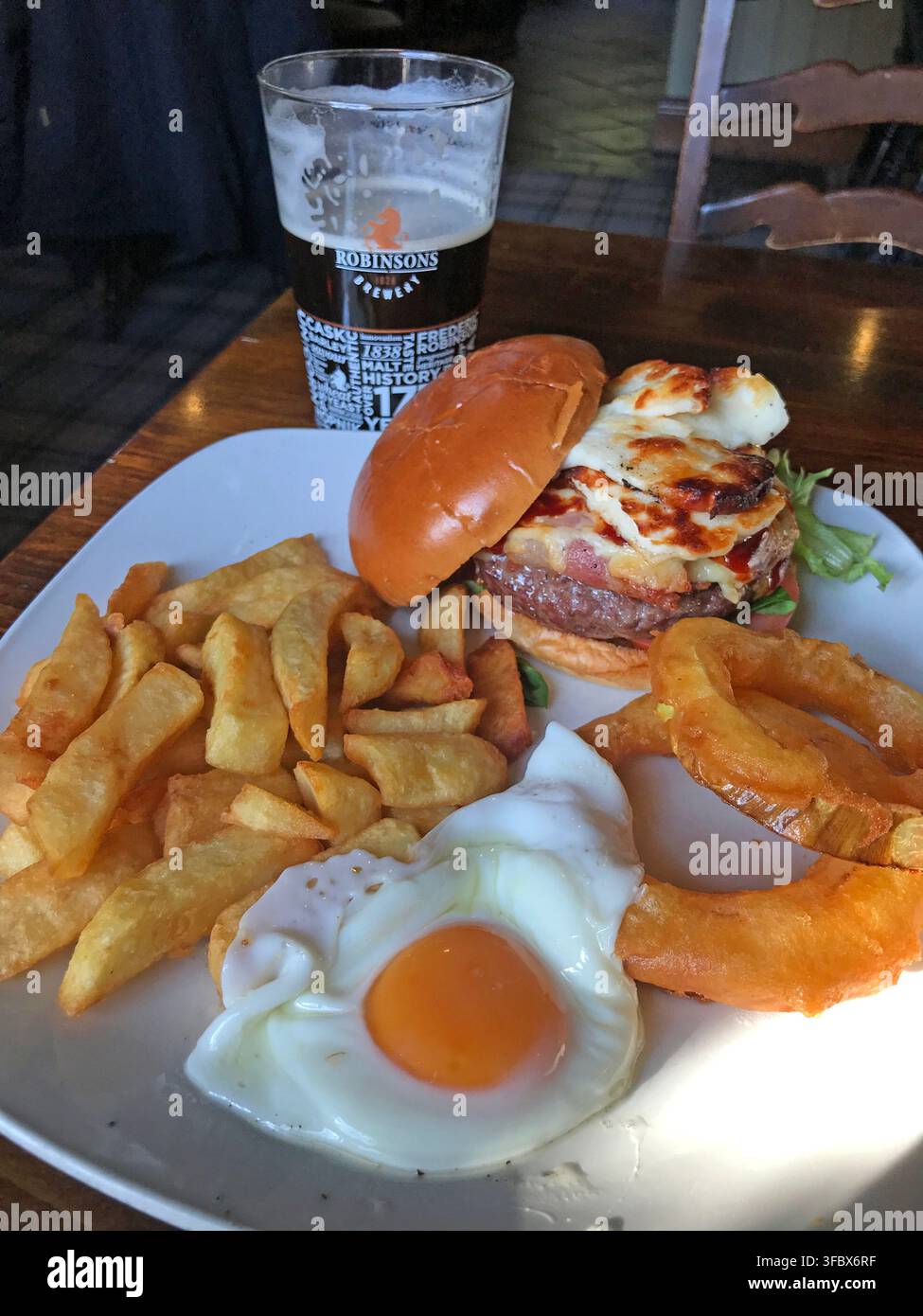 Runny fried egg with burger,chips and beer in a British pub, illustrating UK Salmonella and imported sourced egg safety concerns in August 2026 by FSA Stock Photo