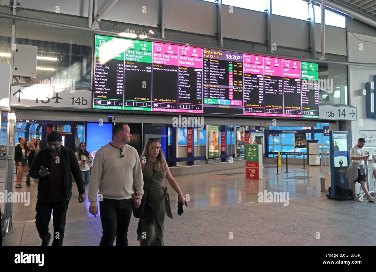 Passengers beneath live electronic departure boards inside Manchester Piccadilly railway station, bottleneck platforms 13 & 14 , England, UK. Stock Photo