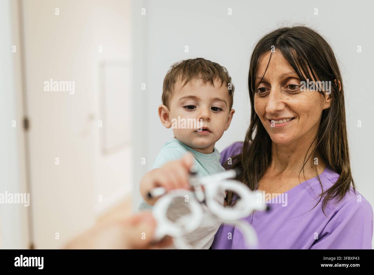 Optometrist holding trial frame in front of baby boy during eyesight testing Stock Photo