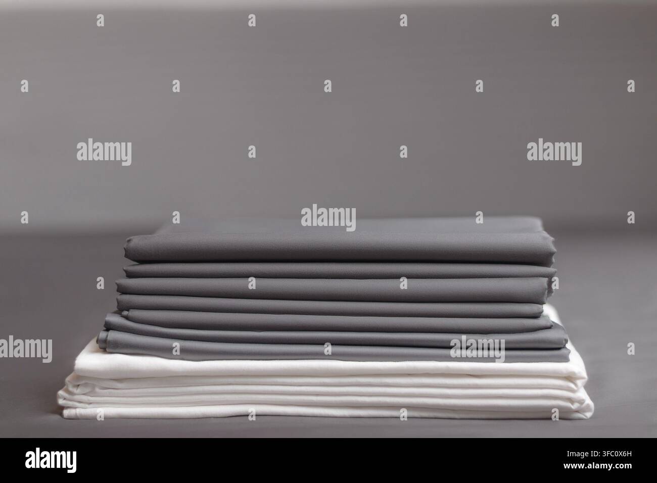 A stack of folded clean gray and white sheets Stock Photo