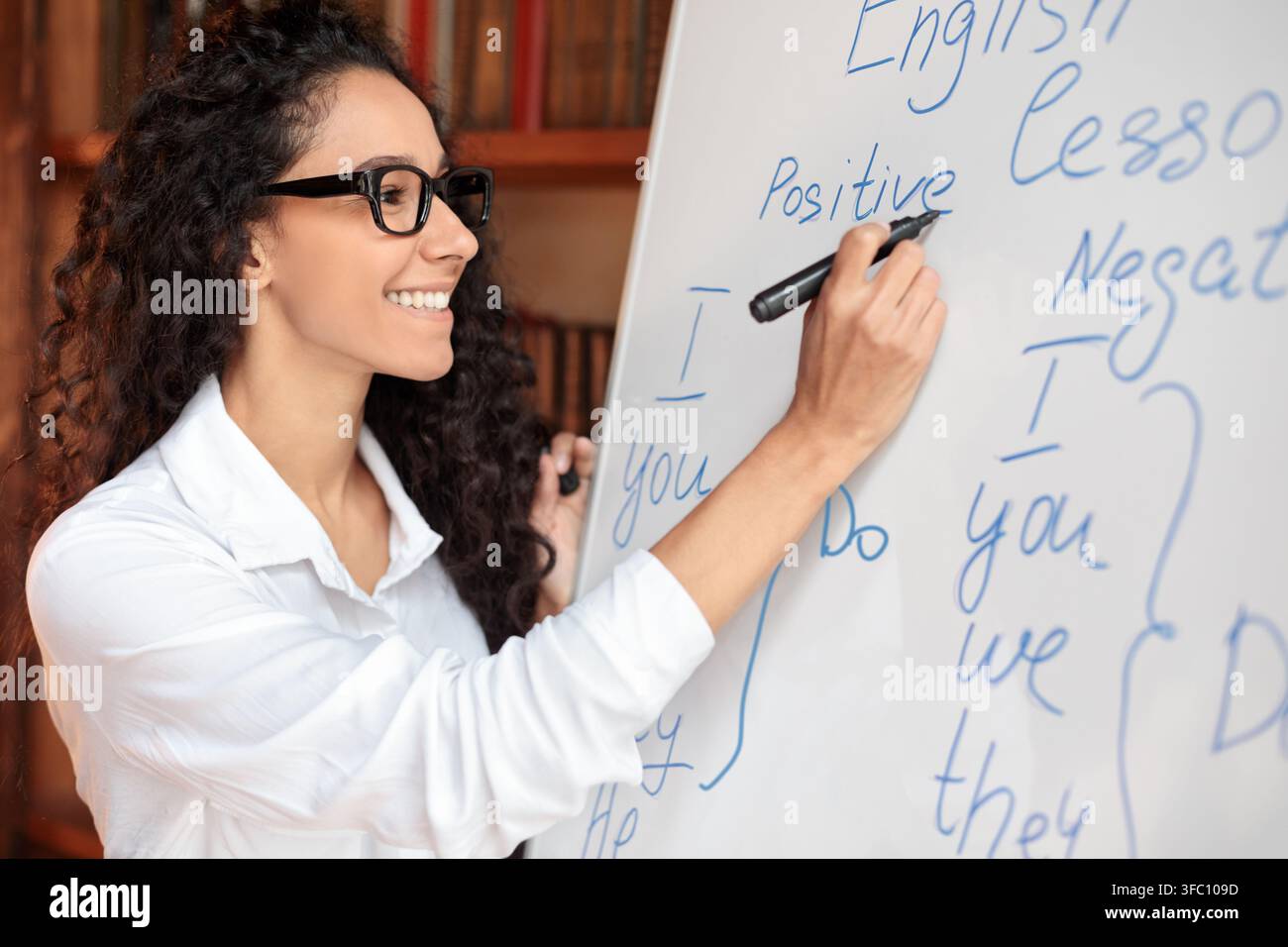 English teacher standing at whiteboard, writing rules on the board Stock Photo