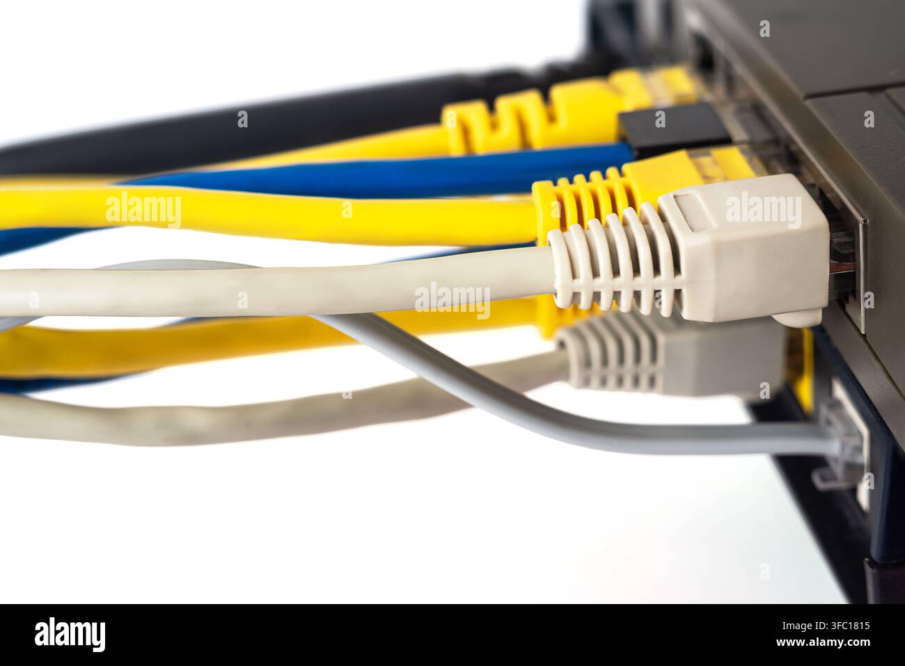 Cables connect to a router with various colors including yellow, blue, and gray in a simple workspace. Stock Photo