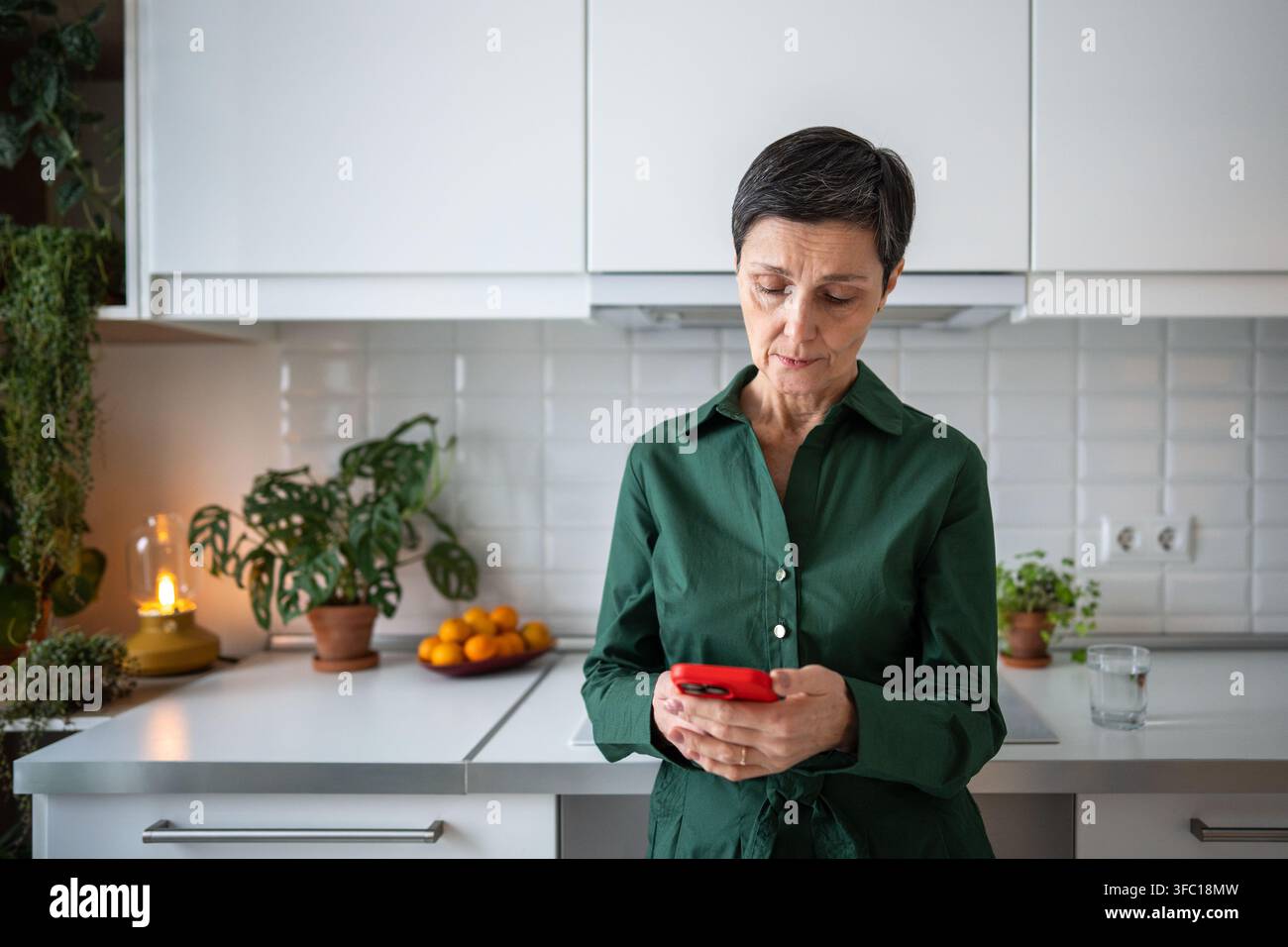 Senior woman reading SMS on mobile phone, deep in thought, thinking, looking puzzled and worried. Stock Photo