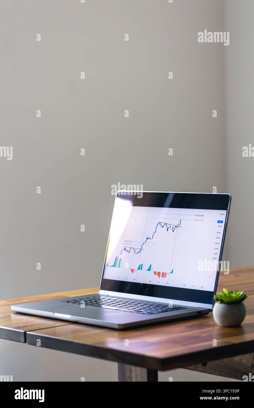 Laptop displaying financial chart on wooden table. Online trading with copy space. Stock Photo