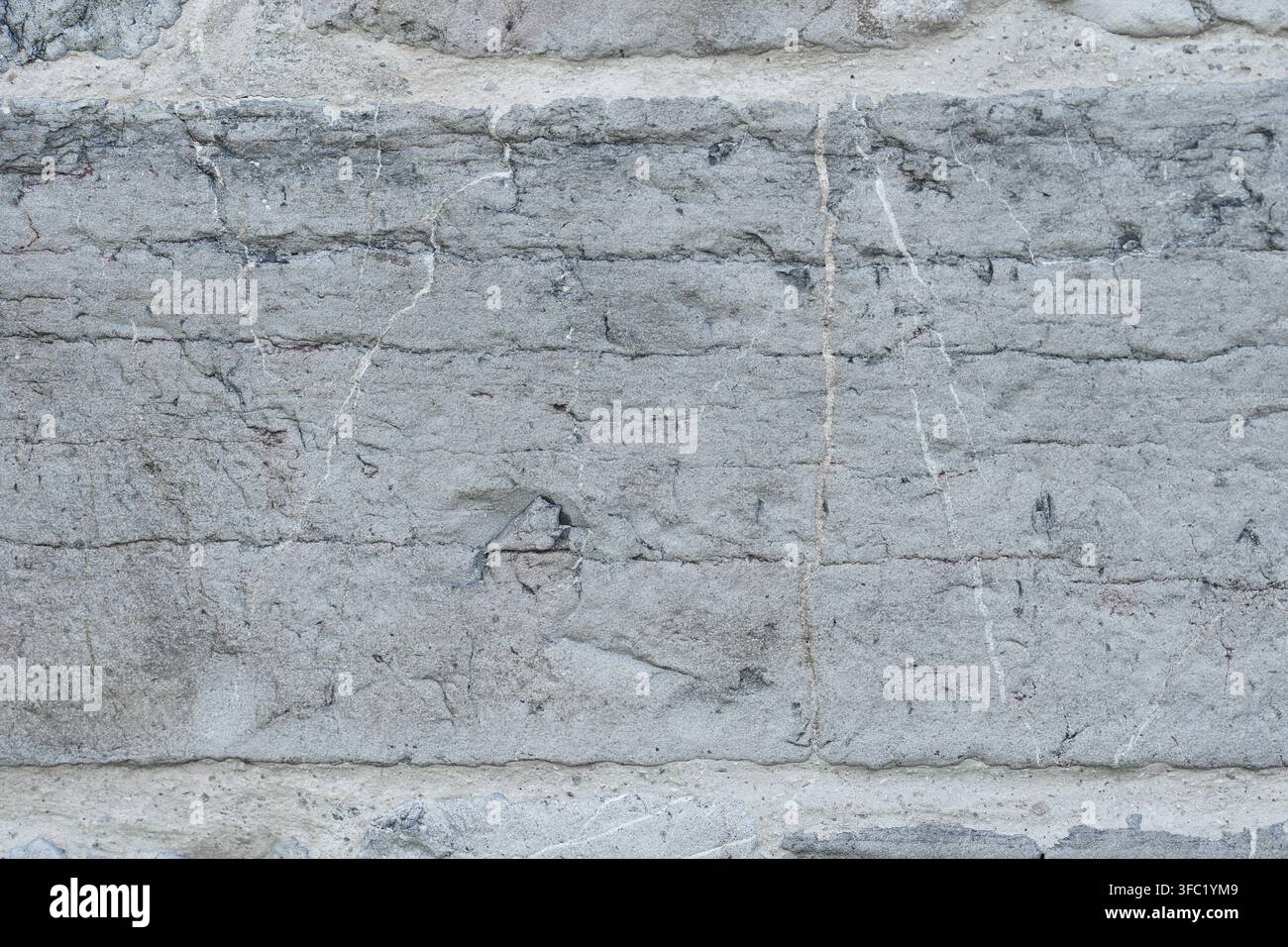 Aged gray masonry wall with rough rectangular stone block. Cracks and weathered surface. Architectural background Stock Photo