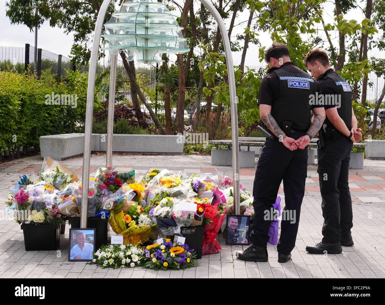 Police officers look at flowers at the Cleveland Police HQ in Middlesbrough, following the line-of-duty deaths of PC Matthew Blades and PC Tom Clough who died when a car going in the wrong direction hit a police car on the A66 near Middlesbrough. Picture date: Tuesday August 25, 2026. Stock Photo