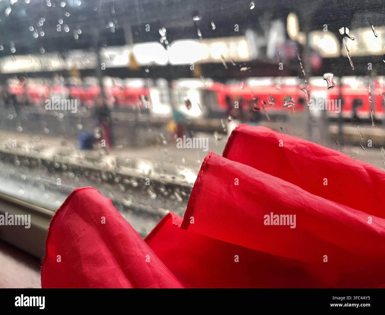 Red red umbrella seen through a rain-covered window on a train Stock Photo