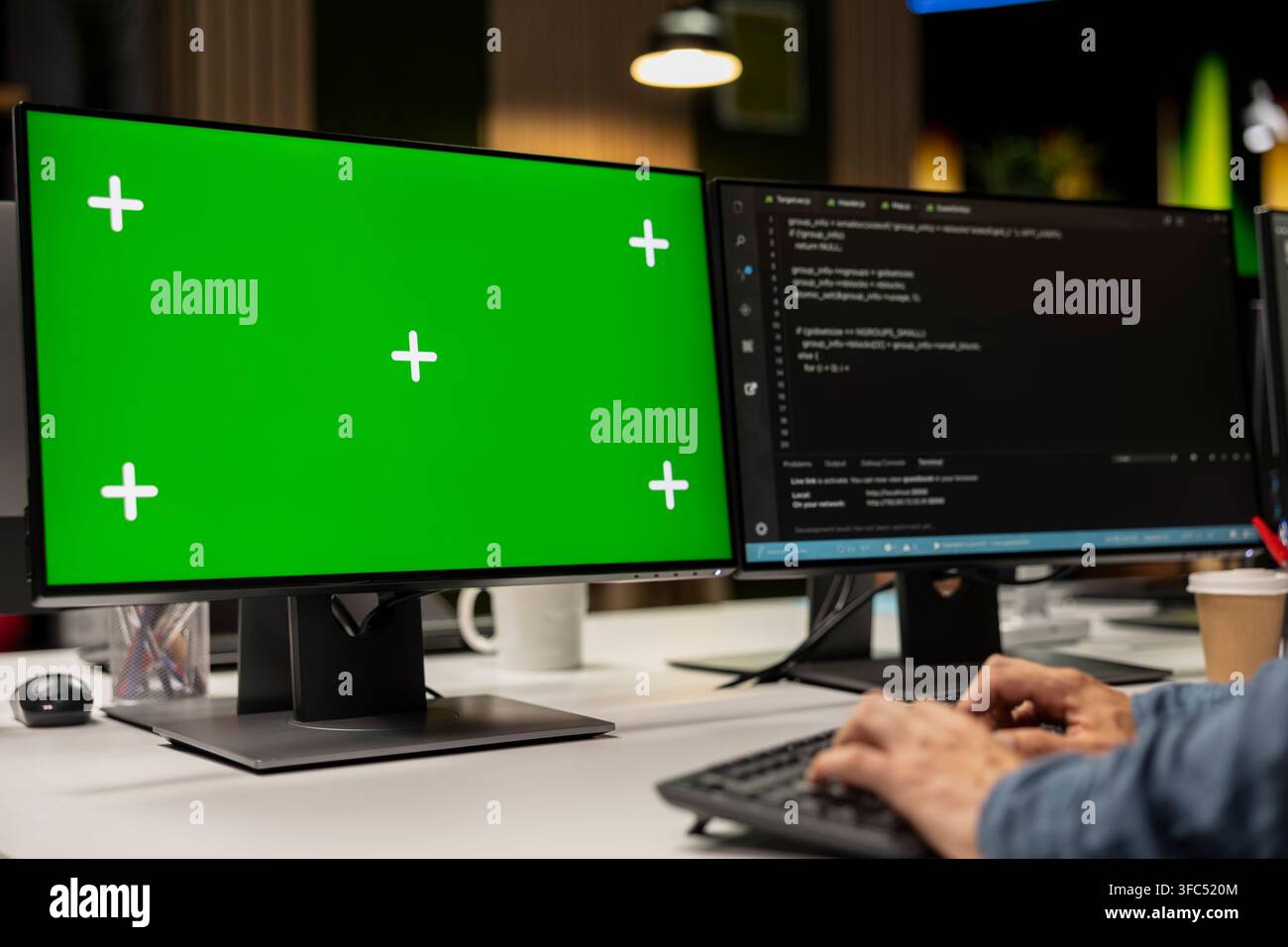 Technician using green screen PC to write code, debugging software issues and improving system stability. IT specialist in tech startup office typing on mockup computer keyboard Stock Photo
