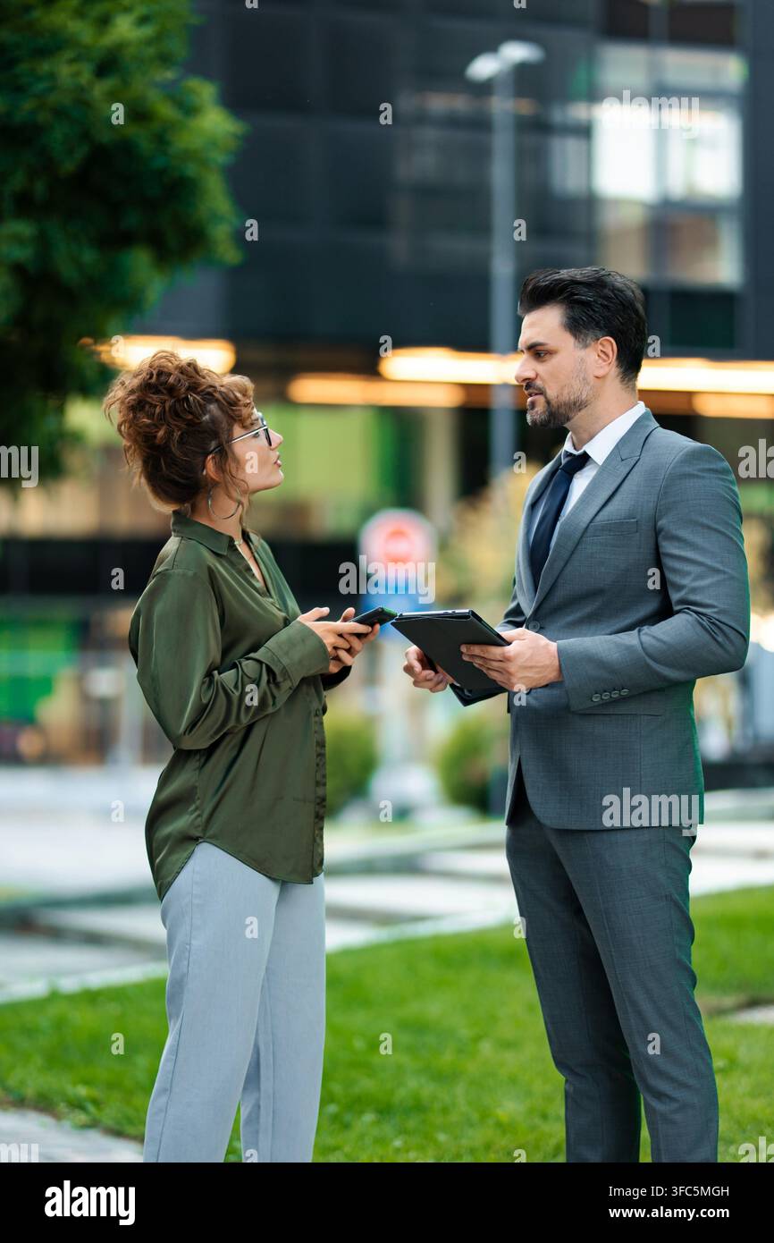 Business colleagues collaborating outdoors using digital tablet and smartphone Stock Photo