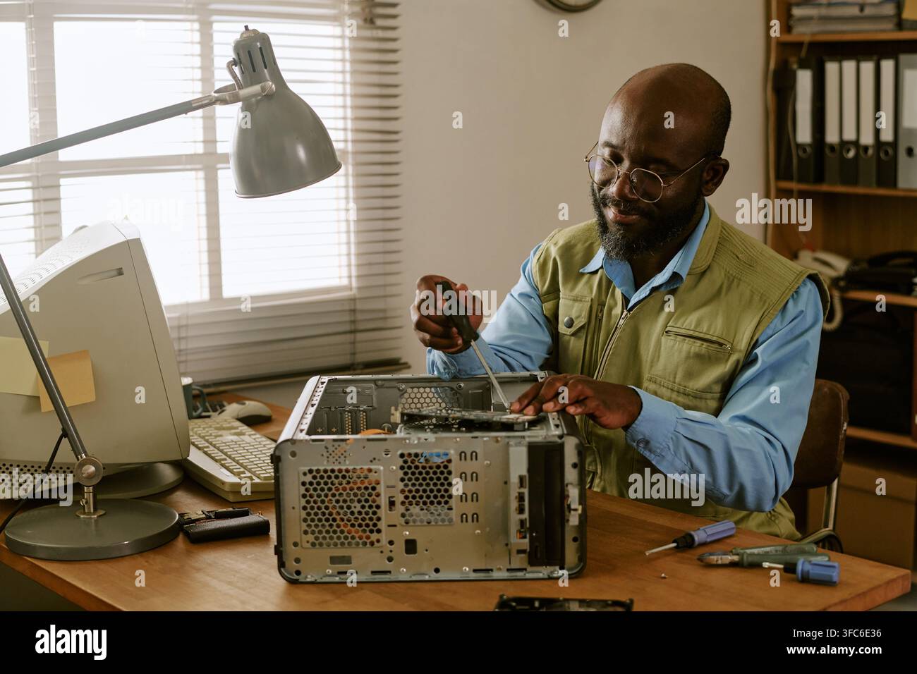 Black Middle Aged Technician Fixing Vintage Computer in Retro Office Stock Photo