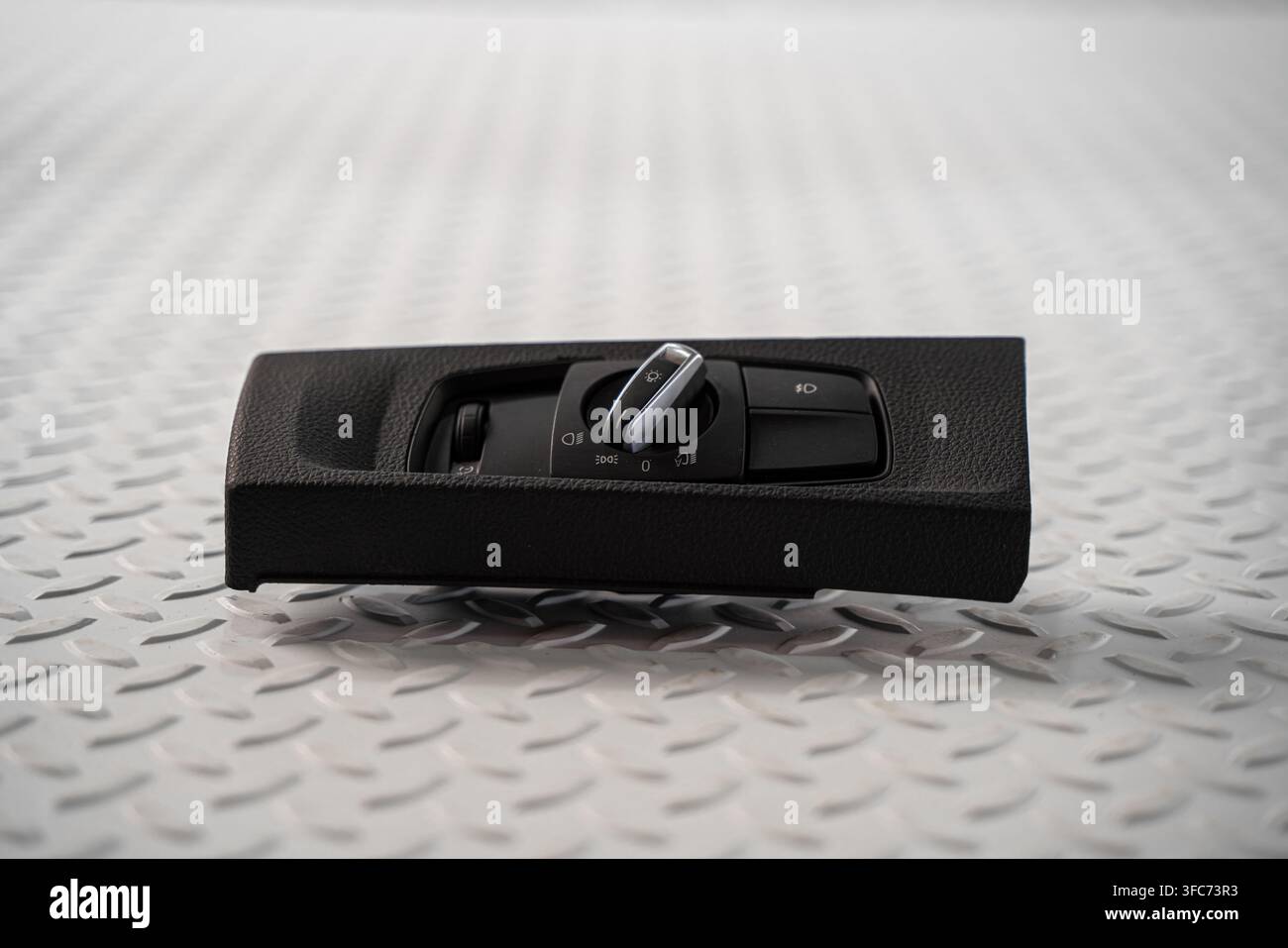 An automotive headlight control switch panel with rotary lighting selector is isolated on a white studio background. Stock Photo