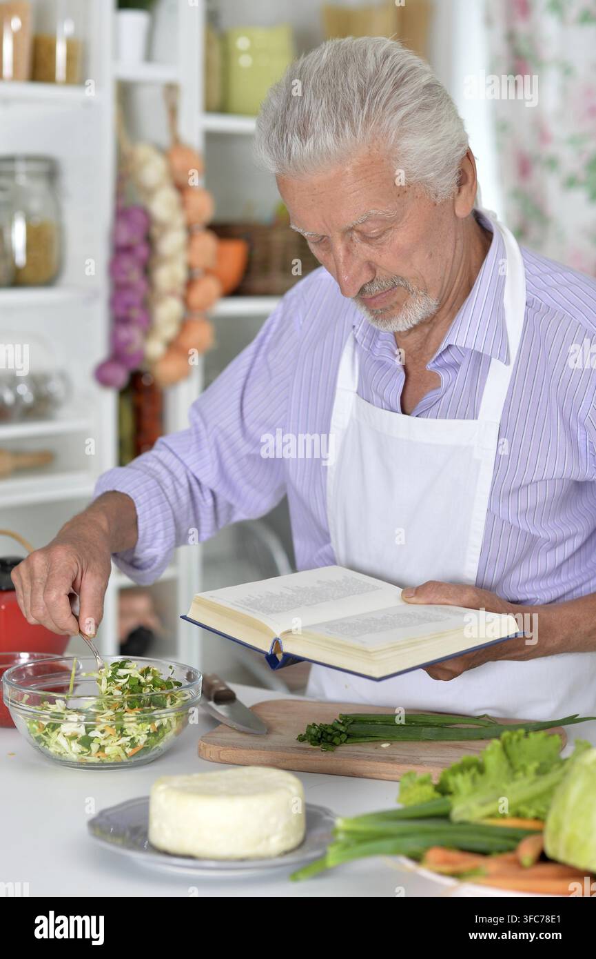 Elderly man in apron preparing healthy food at home Stock Photo