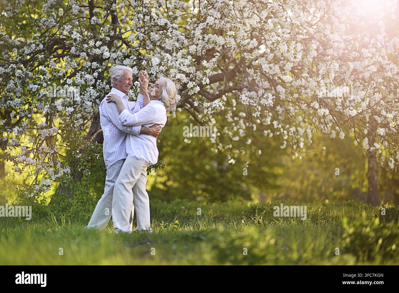 Beautiful elderly couple dancing in apple orchard Stock Photo