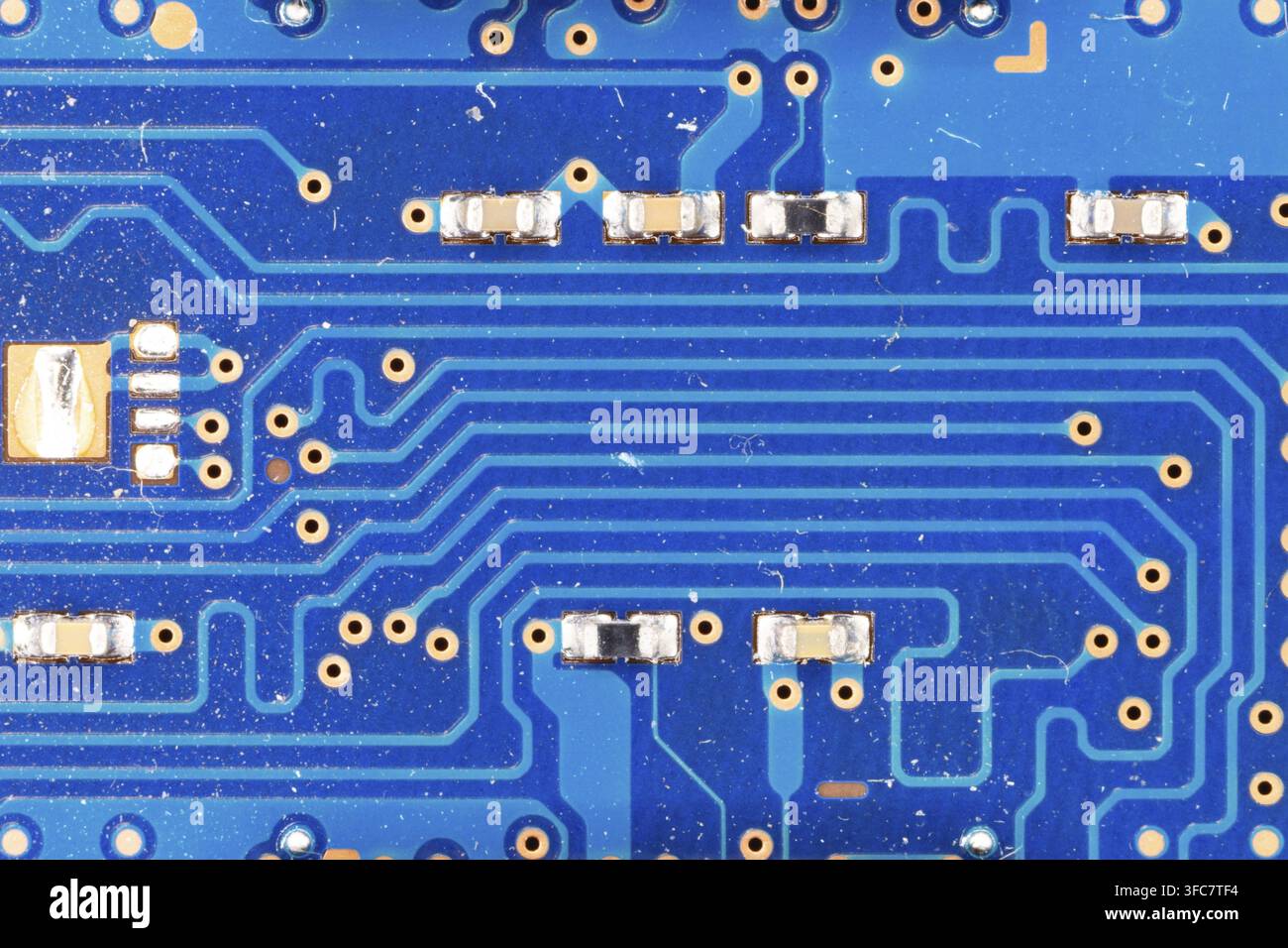 Blue Circuit Board Surface featuring Electronic Pathways and Tiny Components Stock Photo