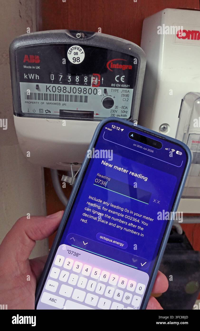 Smartphone showing an Octopus Energy meter-reading screen beside a domestic electricity meter after the October 2026 cap rise. Stock Photo