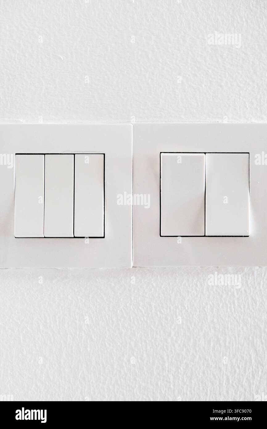 Modern white light switch panels on a clean wall Stock Photo