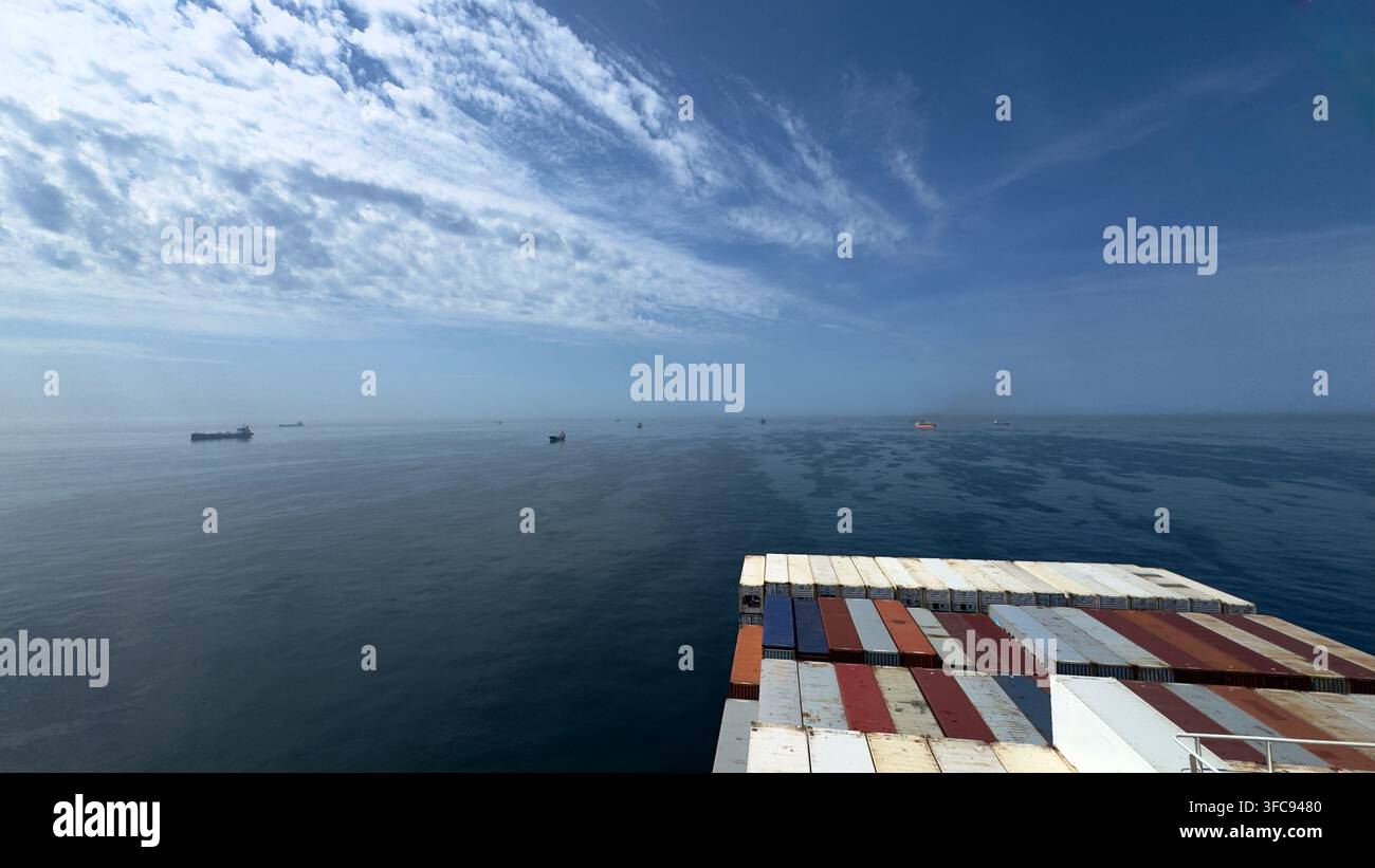 Container ships at sea with shipping containers in the foreground under a dramatic cloudy sky - Smartphone Captured Stock Image