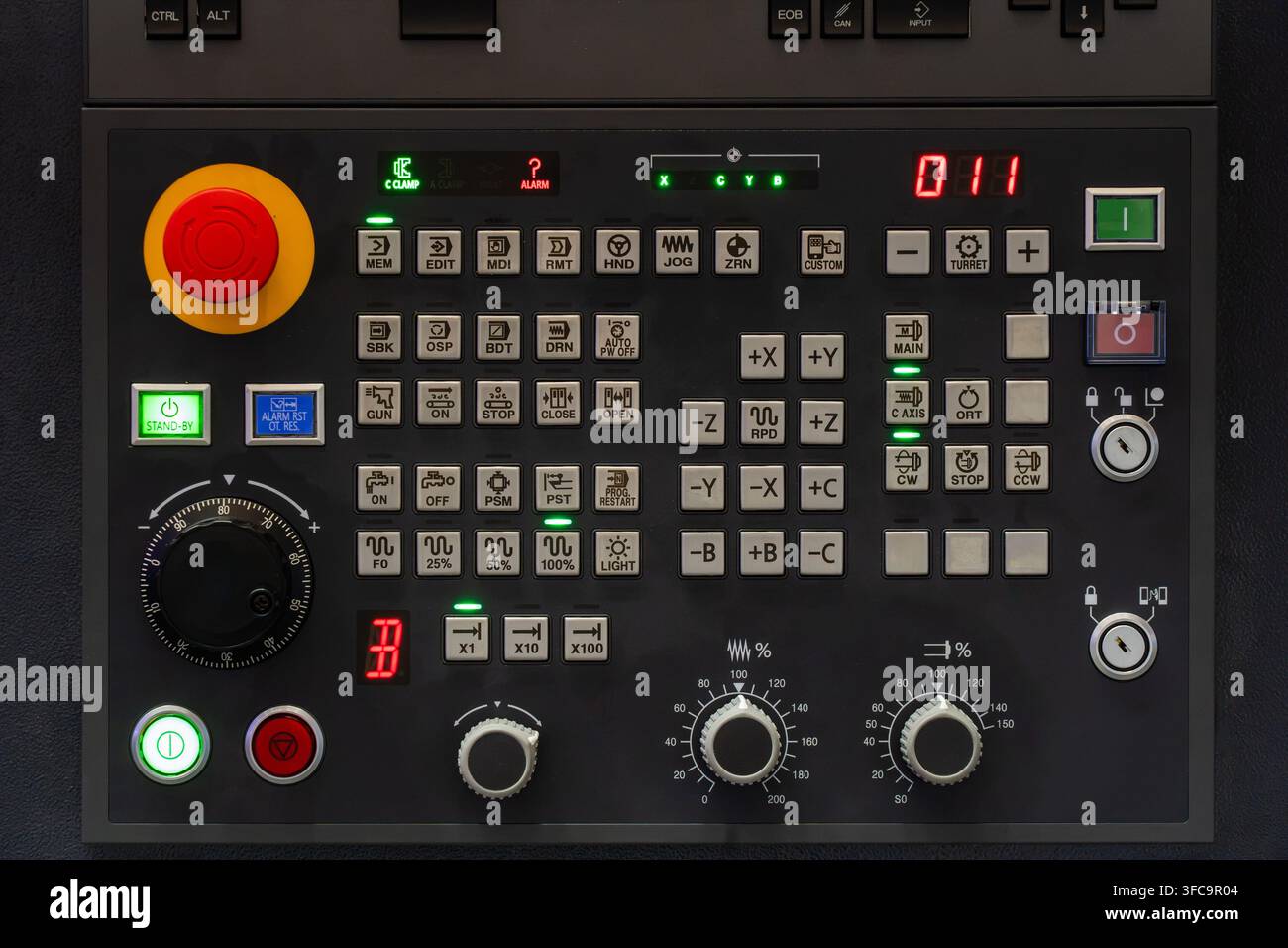 Industrial CNC lathe operator control panel with emergency stop button, rotary dials, function buttons, and LED displays Stock Photo