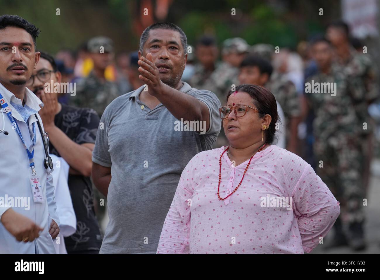 A family stands surrounded by army rescue personnel amidst the ...