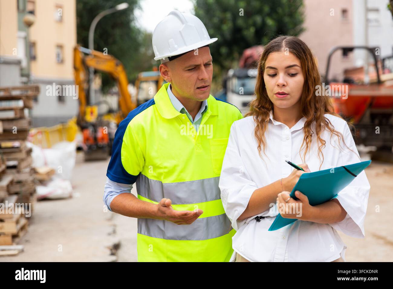 Man engineer and a young woman discuss a construction project while , taking important notes Stock Photo