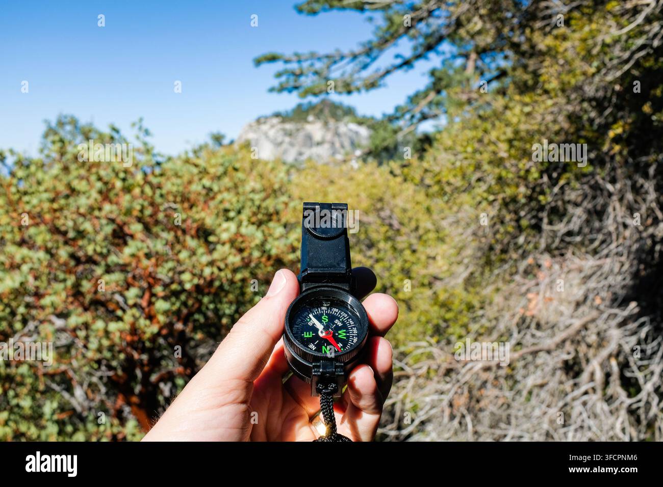 Hand holding a compass while hiking outdoors Stock Photo