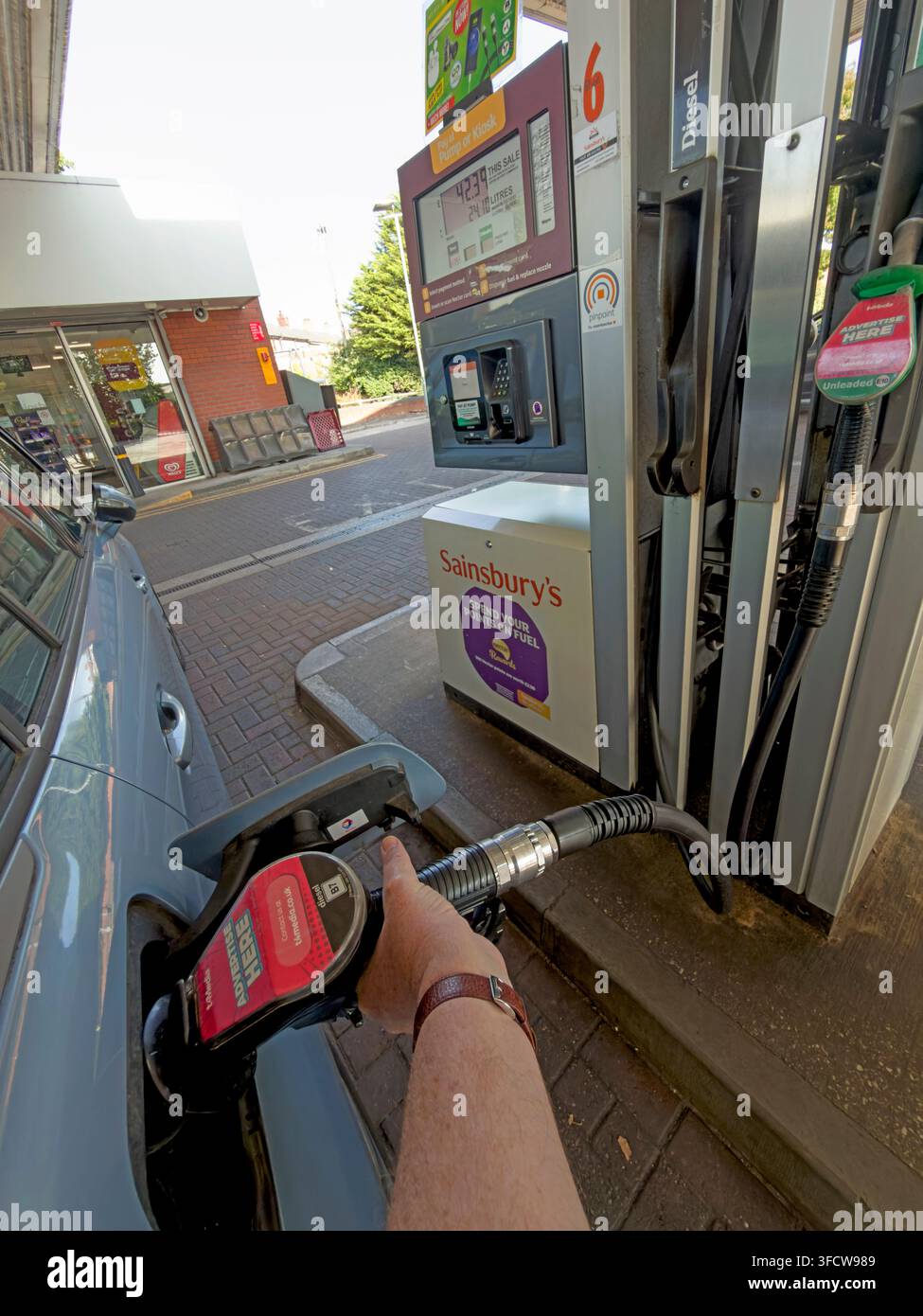 Driver filling a car with diesel at a Sainsbury’s petrol station. Stock Photo