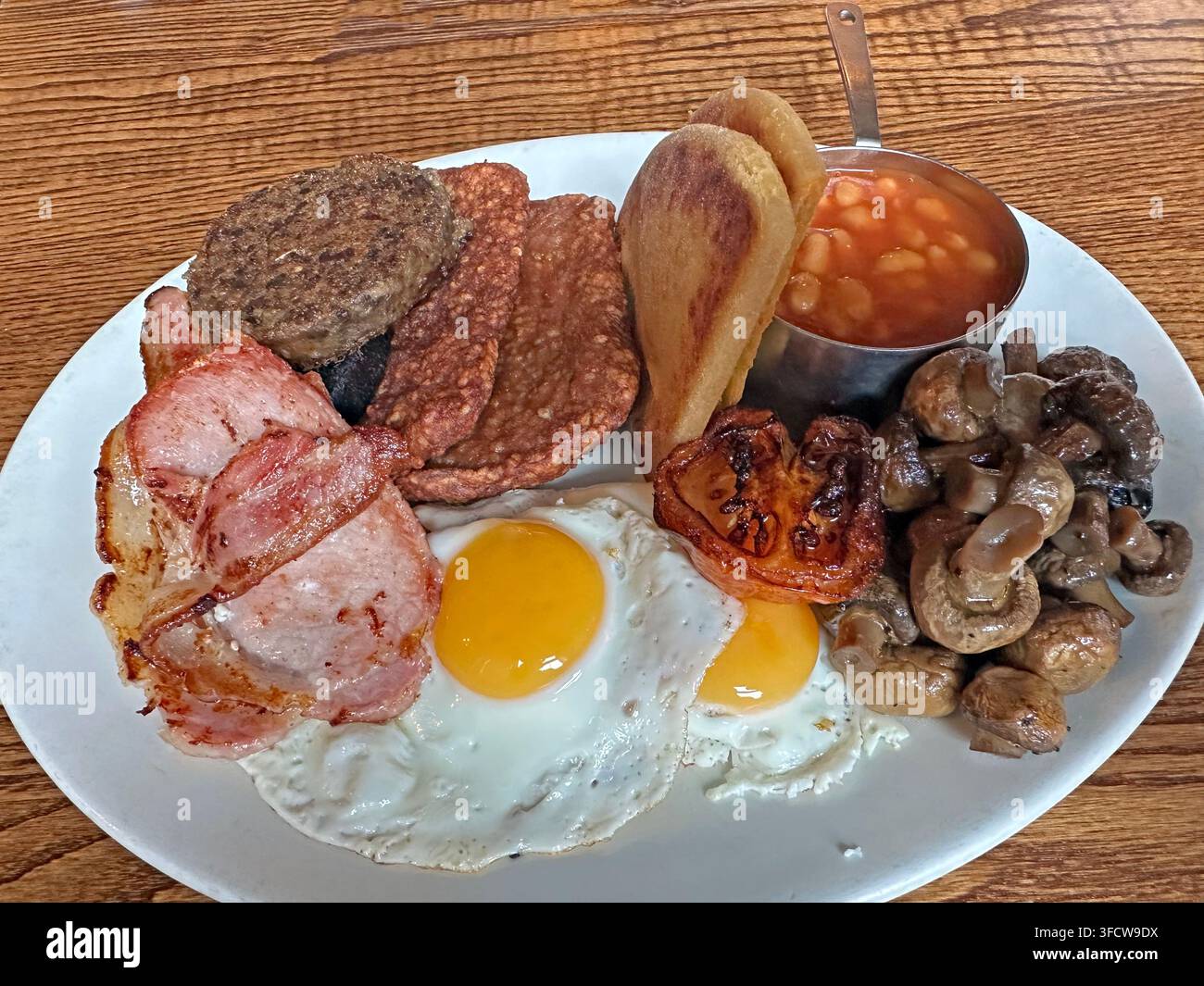 Large Scottish-style cooked breakfast with eggs, bacon, sausage, black pudding, mushrooms, beans and haggis. Stock Photo
