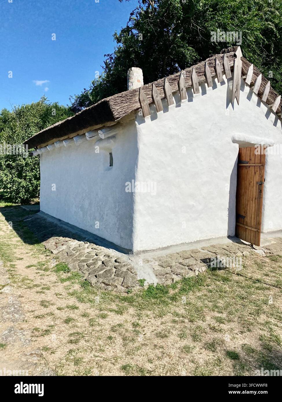 1. Description Traditional whitewashed house with thatched roof under bright summer sunlight. - Smartphone Captured Stock Image