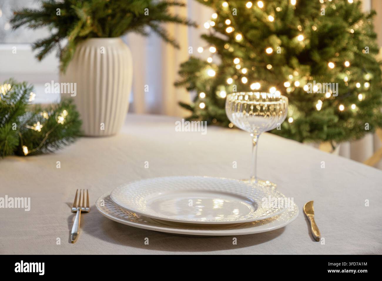 Elegant Christmas table setting with glowing tree lights Stock Photo