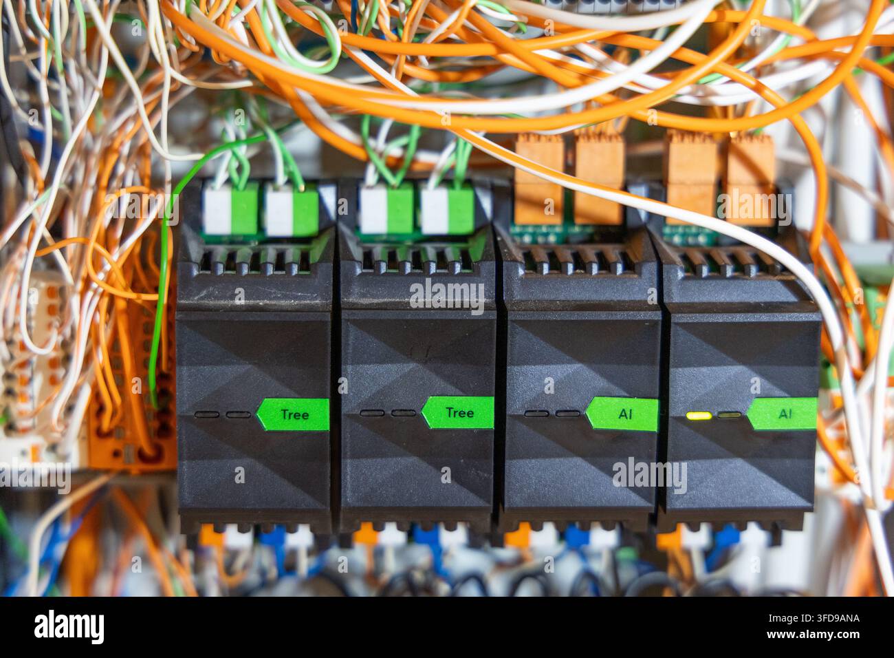 A detailed view of a messy electrical control panel featuring numerous wires, relays, and programmable logic controller modules Stock Photo