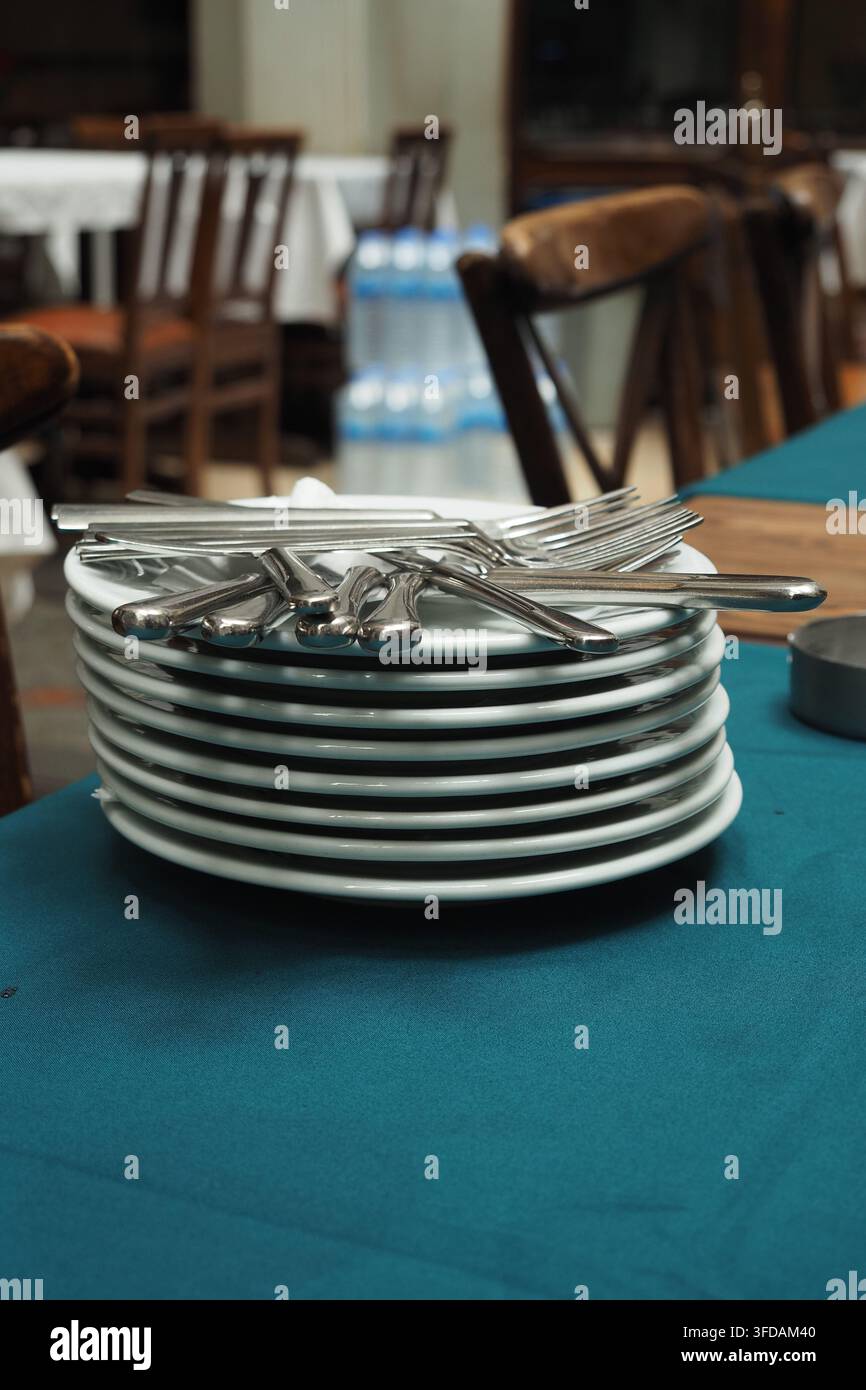 Stack of clean plates and silverware on a table Stock Photo