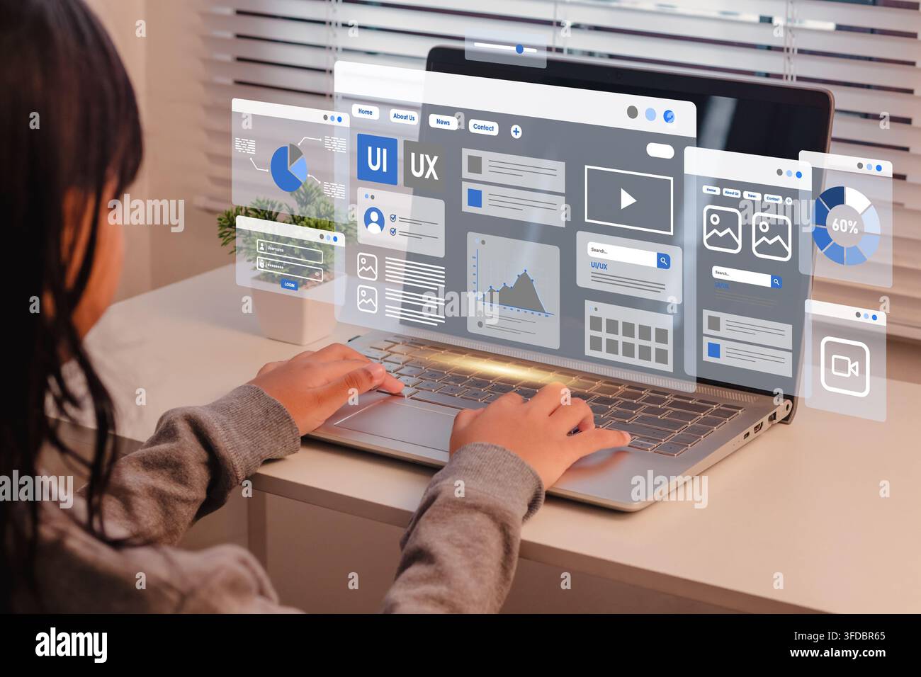 A female student using on a laptop with translucent UI UX design and application layout interfaces Stock Photo