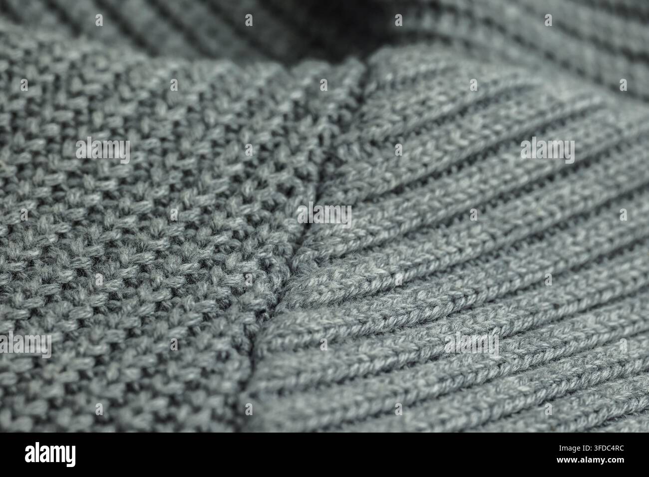Gray knitted wool fabric displaying a textured surface with different stitch patterns Stock Photo