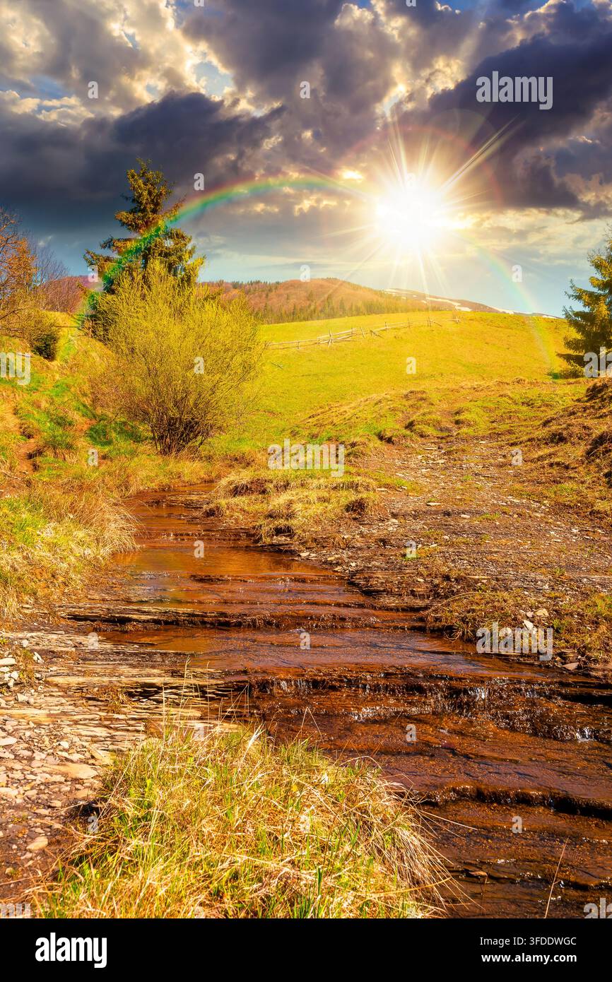 sunset over rural scenery in carpathian mountains. simple view of a countryside mountain landscape during springtime. brook near the grassy hills. wea Stock Photo