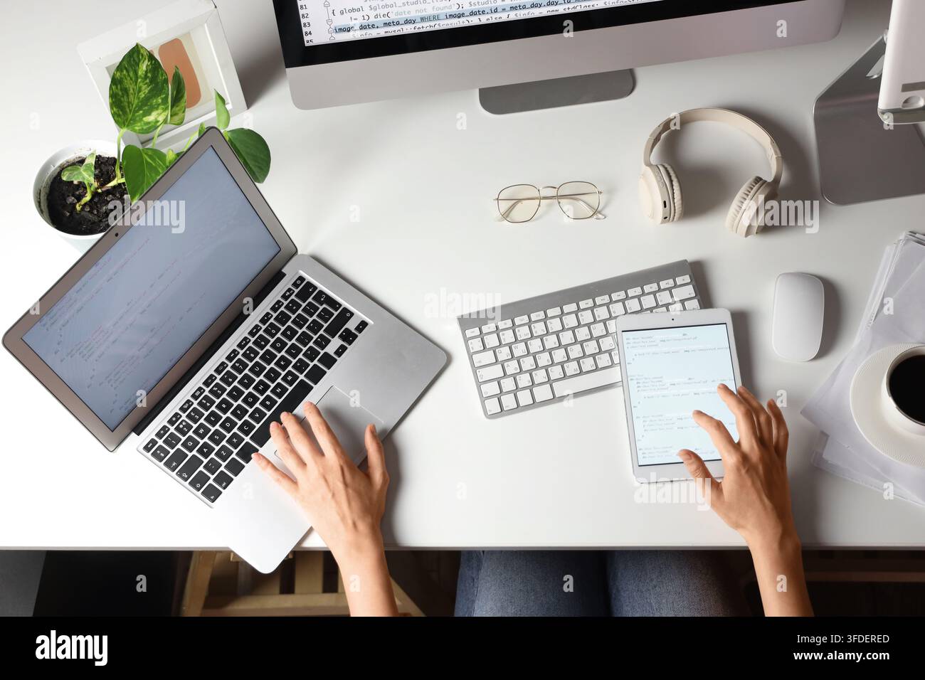 Female programmers hands working with laptop and tablet computer on table, top view Stock Photo
